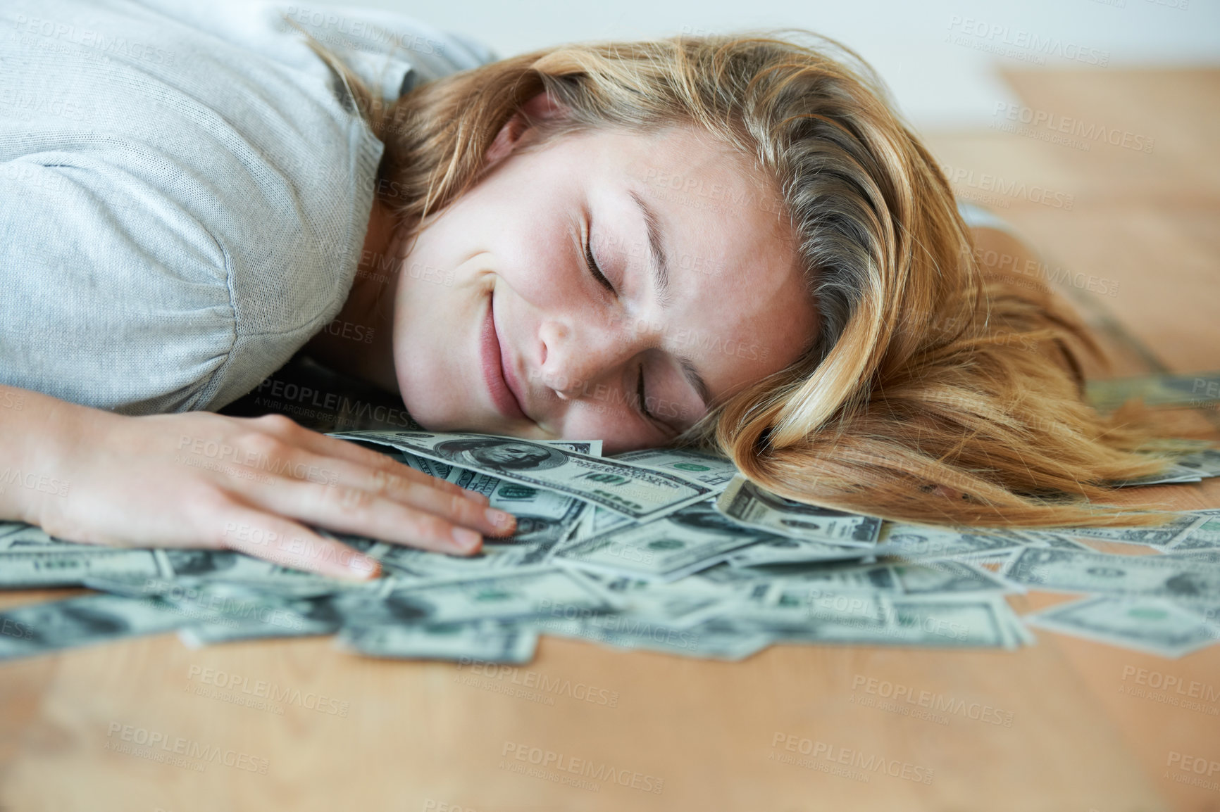 Buy stock photo A smiling girl with her eyes closed lying down on the floor with her head in a pile of money
