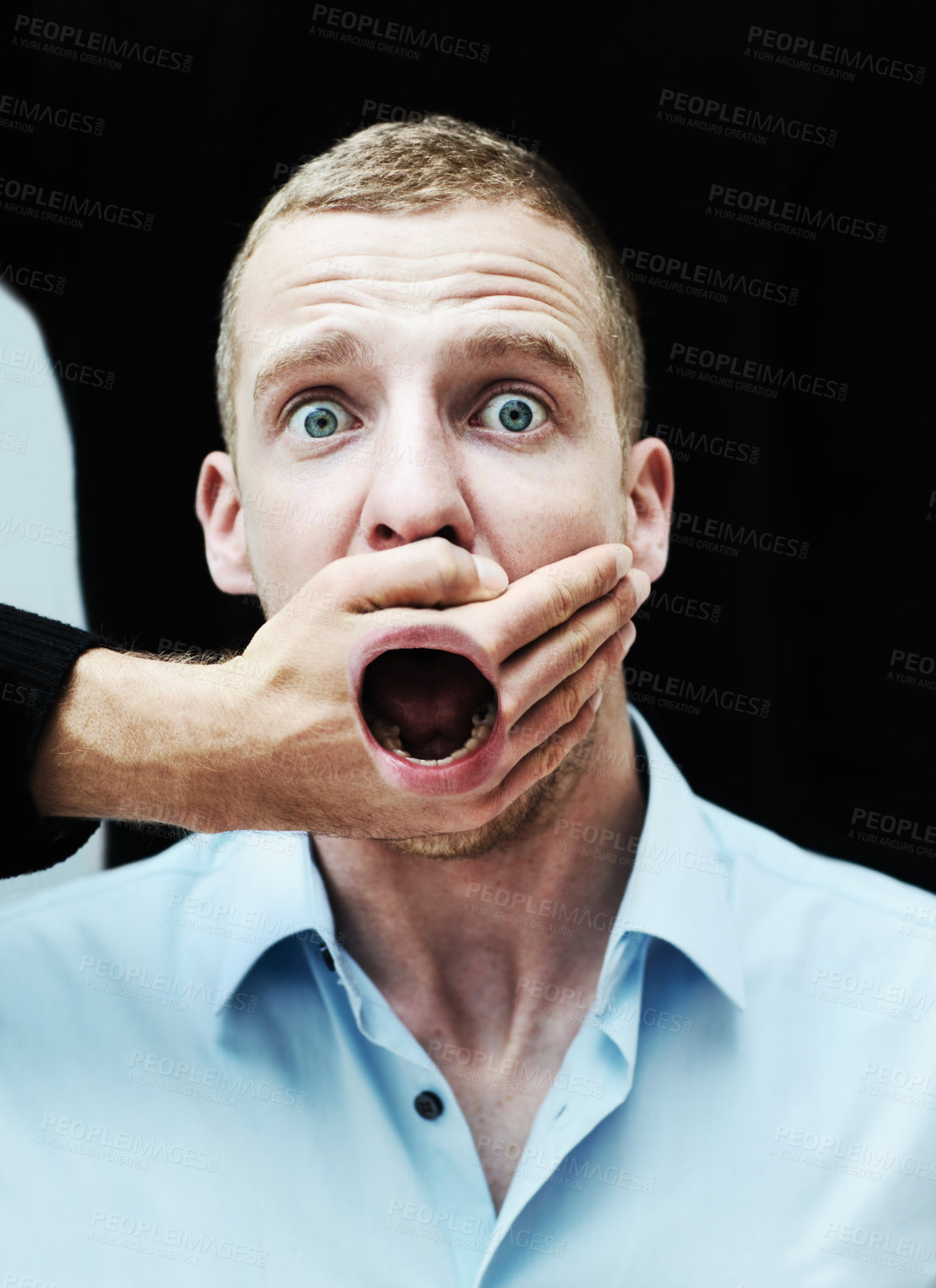 Buy stock photo A distraught looking man with his mouth showing through the hand trying to silence him