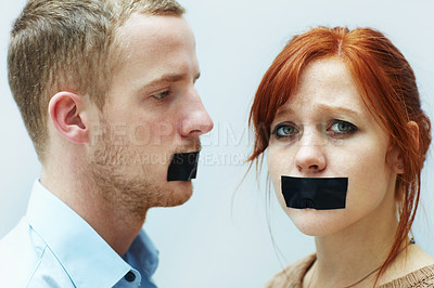 Buy stock photo A young couple looking sad with tape over their mouths