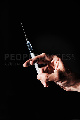 Buy stock photo A hand holding a syringe against a black background