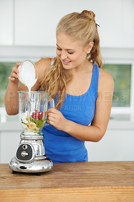 Buy stock photo Attractive young woman making a fruit smoothie