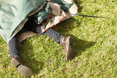 Buy stock photo Closeup of male legs sticking out of a tent. Amateur camper trapped under a camping tent after failing to set it up