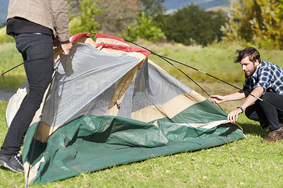 Buy stock photo People, camping and building a tent in nature, countryside and environment with stick in grass. Adventure, shelter and teamwork for pitching equipment to ground for secure outdoor camper structure