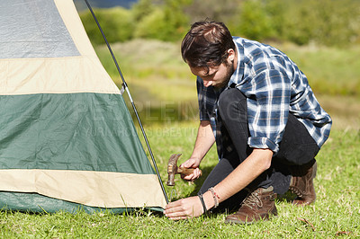 Buy stock photo Camping, tent and man hammer to the ground with building, safety and setup on grass. Adventure, shelter and person start with pitching equipment to green field for secure outdoor structure in nature