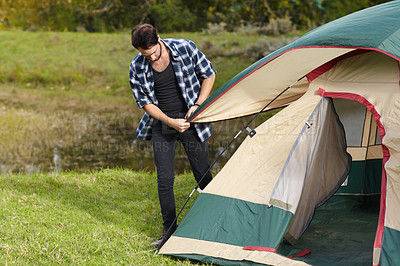 Buy stock photo Nature, camping and man setup a tent in countryside with safety and security in grass field. Adventure, shelter and person start with pitching equipment to ground for secure outdoor camper structure