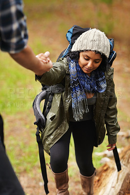Buy stock photo Young woman receiving a helping hand from her boyfriend while out hiking