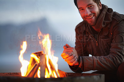 Buy stock photo Happy man, fire and camping, travel and outdoor in nature, warm up and winter, relax with peace on vacation. Bonfire, flame or campfire for heat and portrait, campsite adventure with wood and comfort
