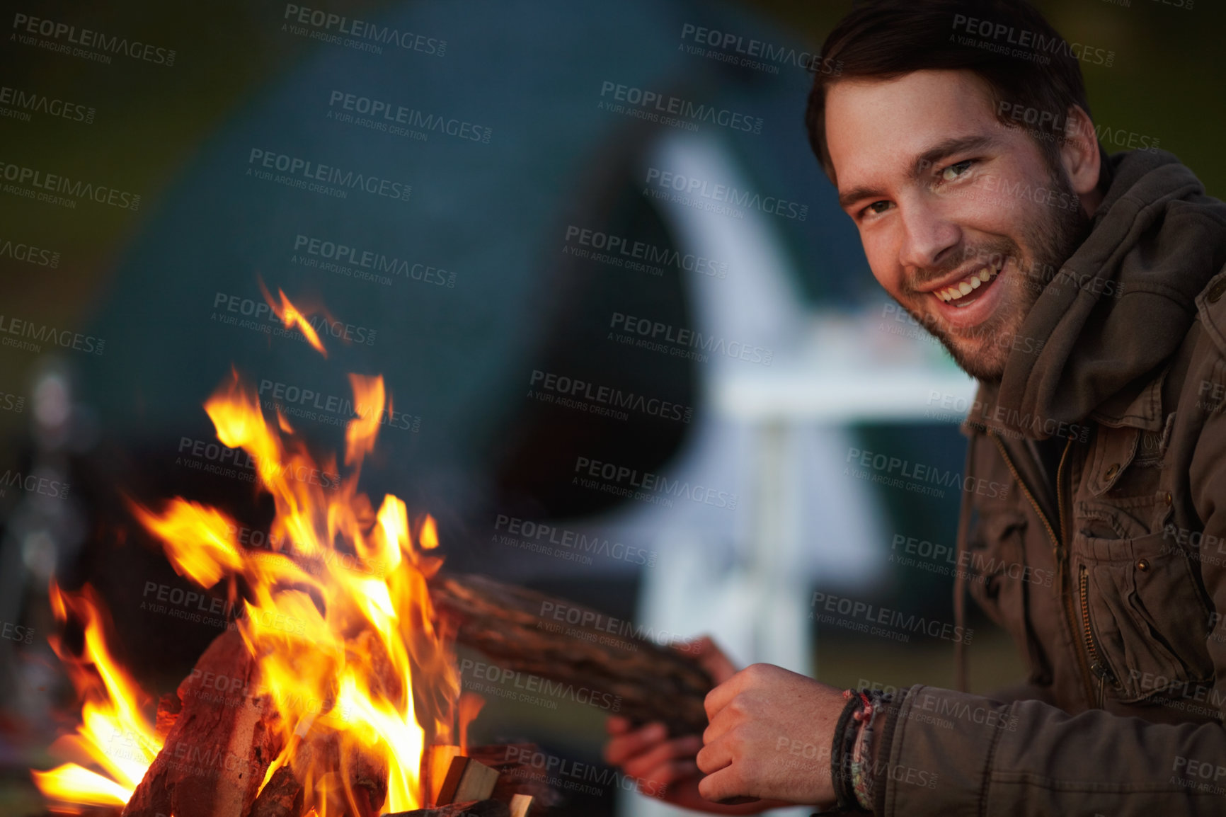 Buy stock photo Happy man, campfire and camping, travel and outdoor in nature, warm up and winter, relax with peace and vacation. Camper, flame or fire for heat and freedom, campsite adventure with wood and comfort