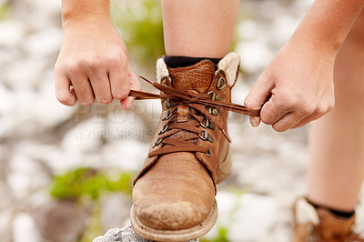 Buy stock photo Cropped view of a young hiker tying his shoe laces