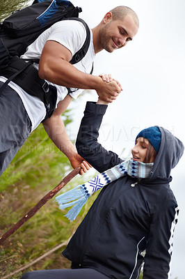 Buy stock photo Helping hand, man and woman on hiking adventure in mountain with nature walk, wellness and support. Travel, trekking and happy couple in countryside holding hands on natural outdoor journey together.