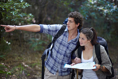 Buy stock photo Couple, map or pointing in forest for hiking, travel or adventure with sightseeing and experience. People, man or woman on trail, holiday or vacation in woods or nature for location, trekking or view