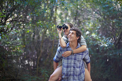 Buy stock photo Man, woman and piggyback outdoor with binocular for travel, adventure or sightseeing in nature with happiness. Couple, people and tourist hiking in woods or forest for experience, holiday or vacation