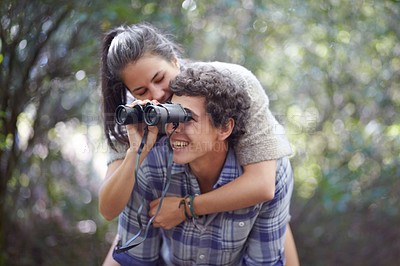 Buy stock photo Man, woman and piggyback in forest with binocular for travel, adventure or sightseeing in nature with happiness. Couple, people and tourist hiking outdoor in woods for experience, holiday or vacation