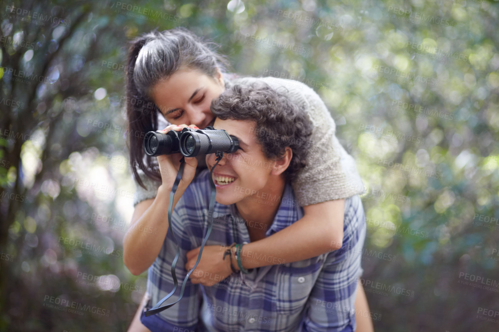 Buy stock photo Man, woman and piggyback in forest with binocular for travel, adventure or sightseeing in nature with happiness. Couple, people and tourist hiking outdoor in woods for experience, holiday or vacation