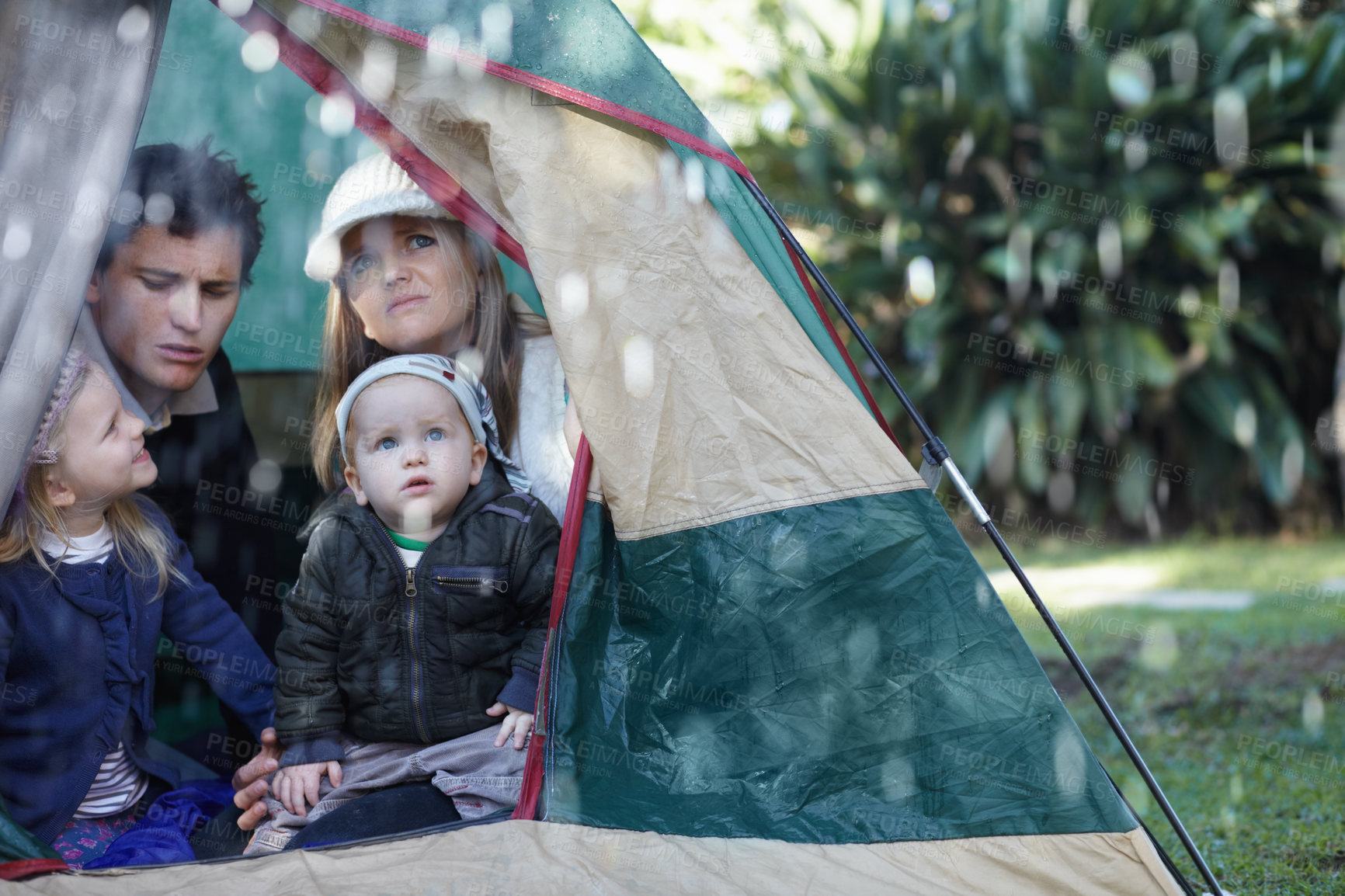 Buy stock photo Young family stuck in their tent during a rainy day