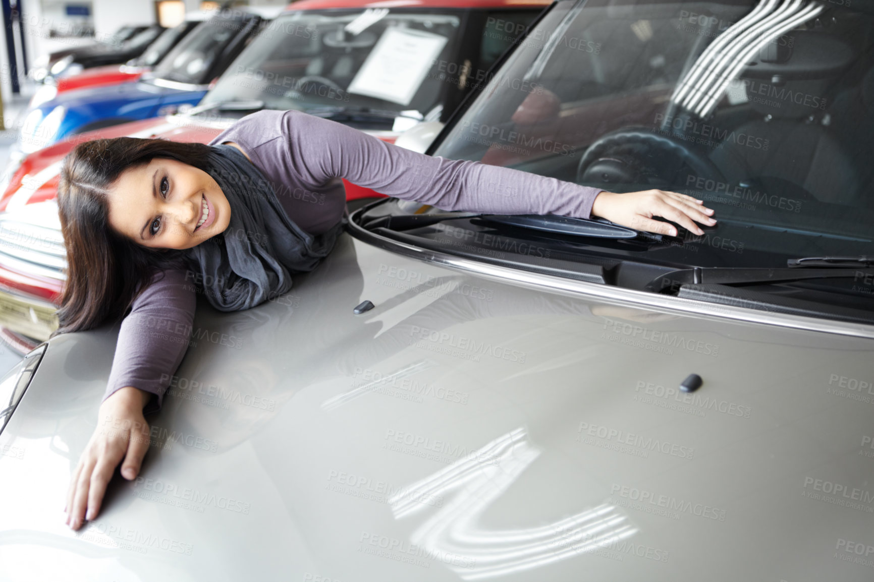 Buy stock photo Beautiful young woman leaning over and lying across the bonnet of a coveted car