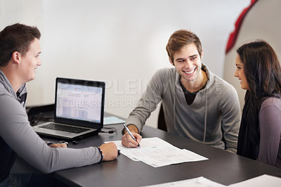 Buy stock photo Shot of a young couple filling out paperwork with an advisor