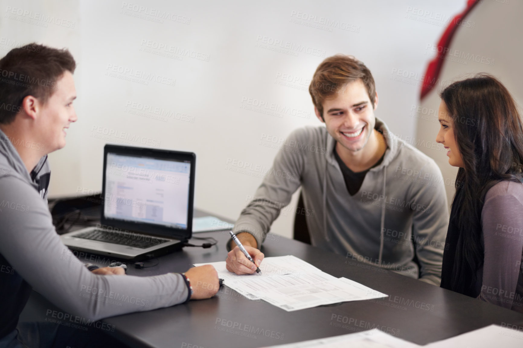 Buy stock photo Shot of a young couple filling out paperwork with an advisor