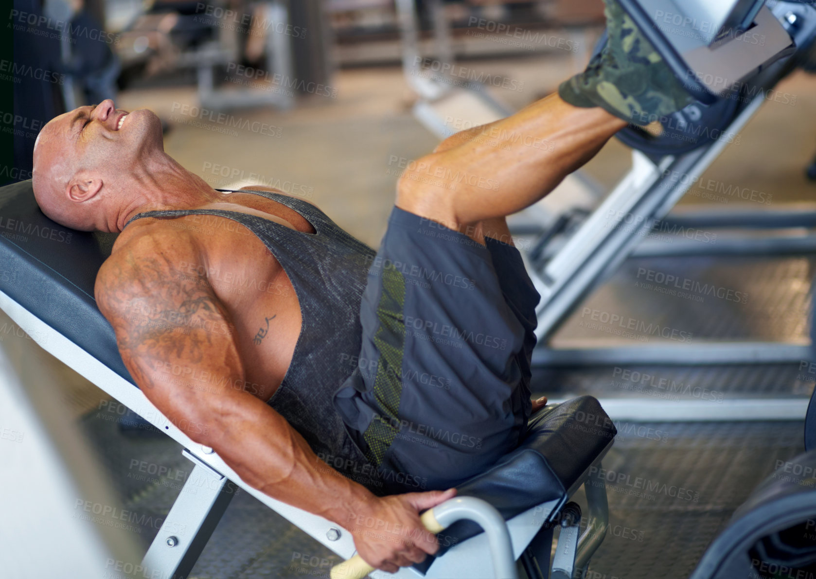 Buy stock photo Shot of a male bodybuilder doing leg exercises on a machine at the gym