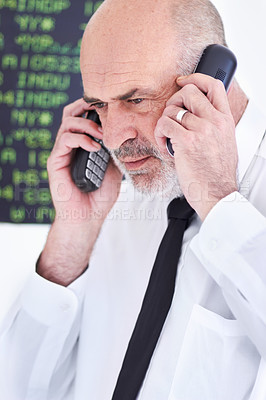 Buy stock photo Shot of a mature stock broker speaking on two mobile phones at once