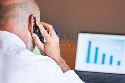 Buy stock photo Rearview shot of a businessman sitting in front of a laptop and talking on his mobile phone