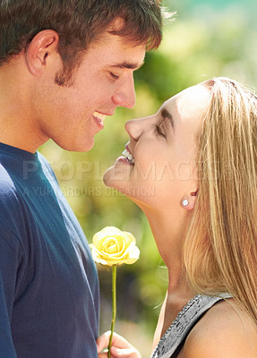 Buy stock photo A young couple looking lovingly at one another while the woman holds a flower