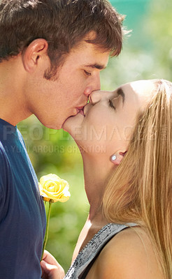 Buy stock photo Love, kiss and happy with couple in nature for romantic, bonding and affectionate. Happiness, flowers and gift with man and woman kissing in garden park on date for spring, care and valentines day