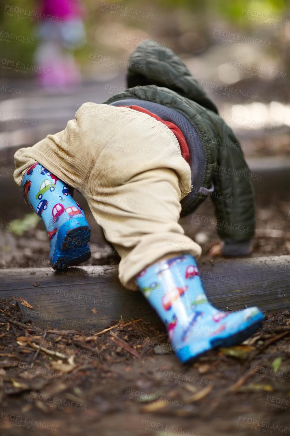 Buy stock photo Rearview of a young boy crawling in the dirt wearing gumboots