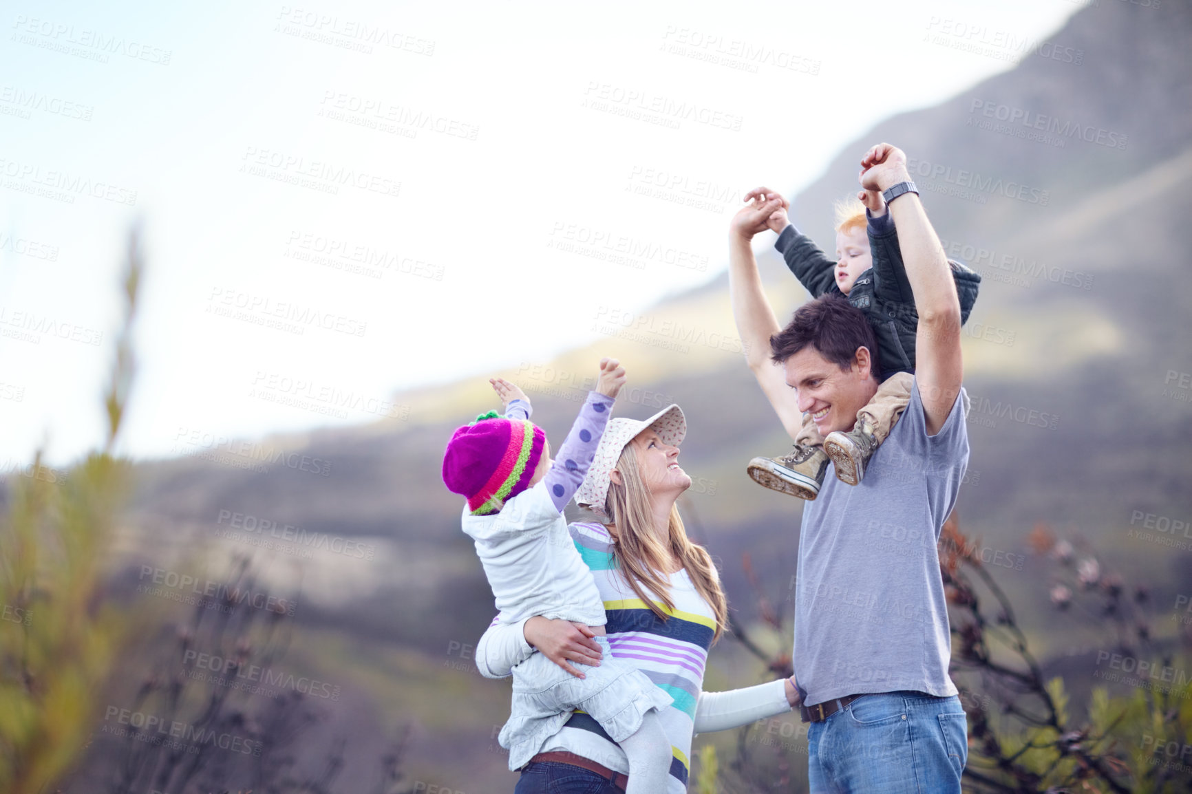 Buy stock photo A young family with the children on their parent's shoulders while out hiking together