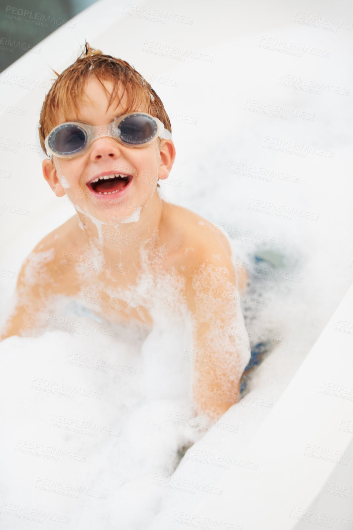 Buy stock photo Children, bath and a boy in swimming goggles having fun while cleaning for hygiene in water. Soap, wellness and bubbles with a happy young kid alone in the bathroom to wash for fresh skincare