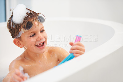 Buy stock photo A cute young boy playing with a snorkel while sitting in the bath with goggles on his head