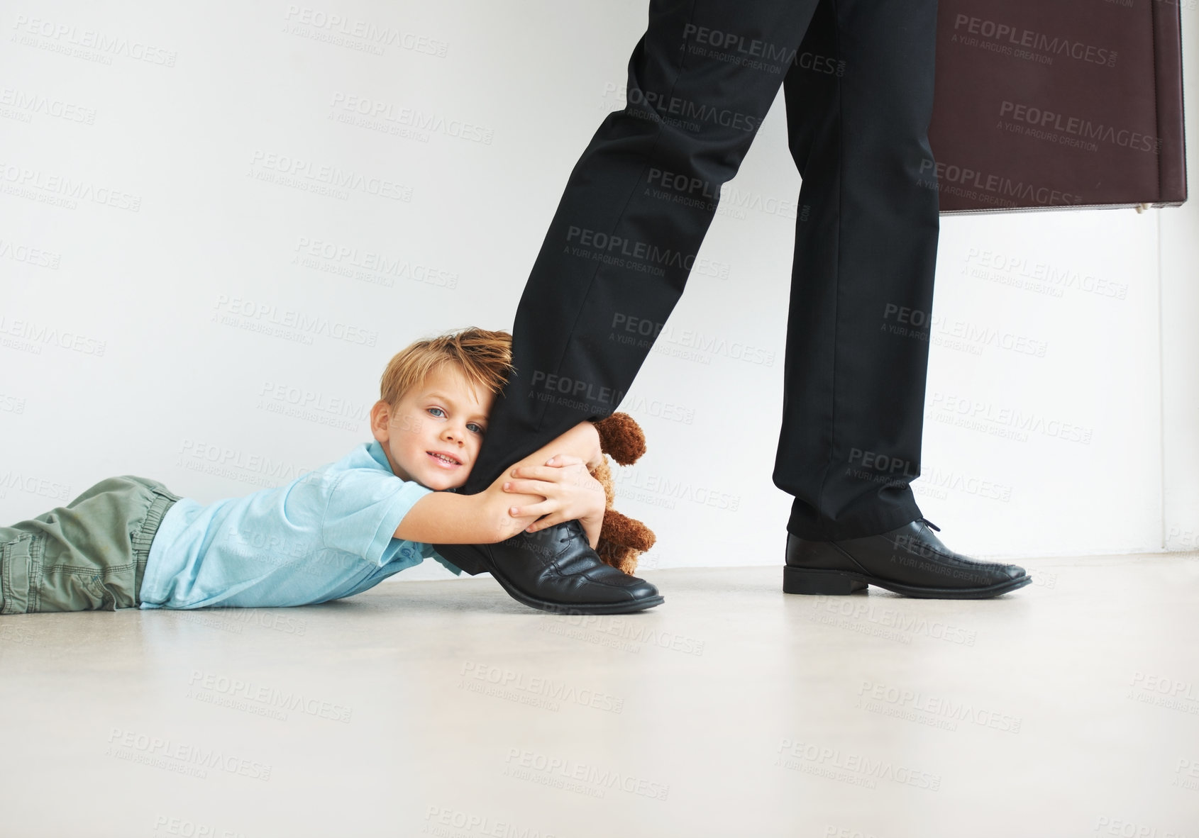 Buy stock photo Portrait of a cute young boy holding onto his dad's leg as he tries to leave for work