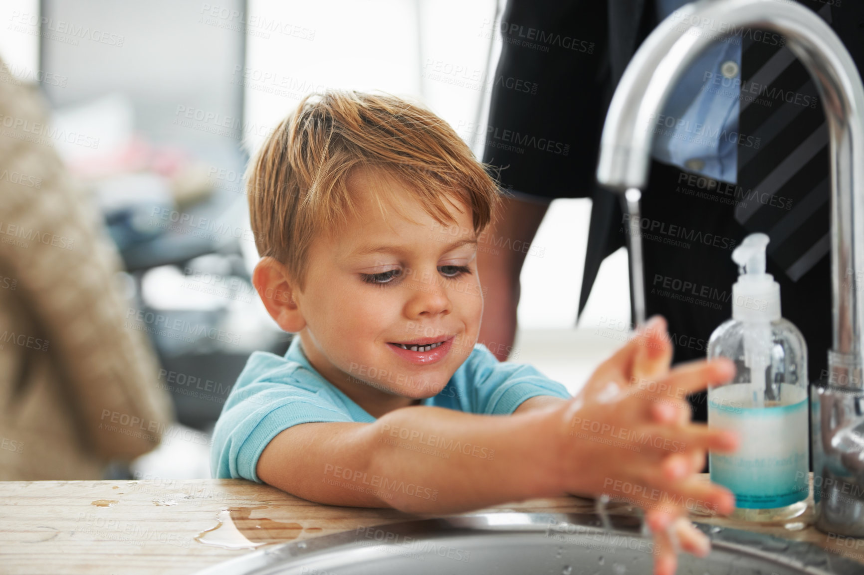 Buy stock photo A cute young boy washing his hands in the kitchen sink