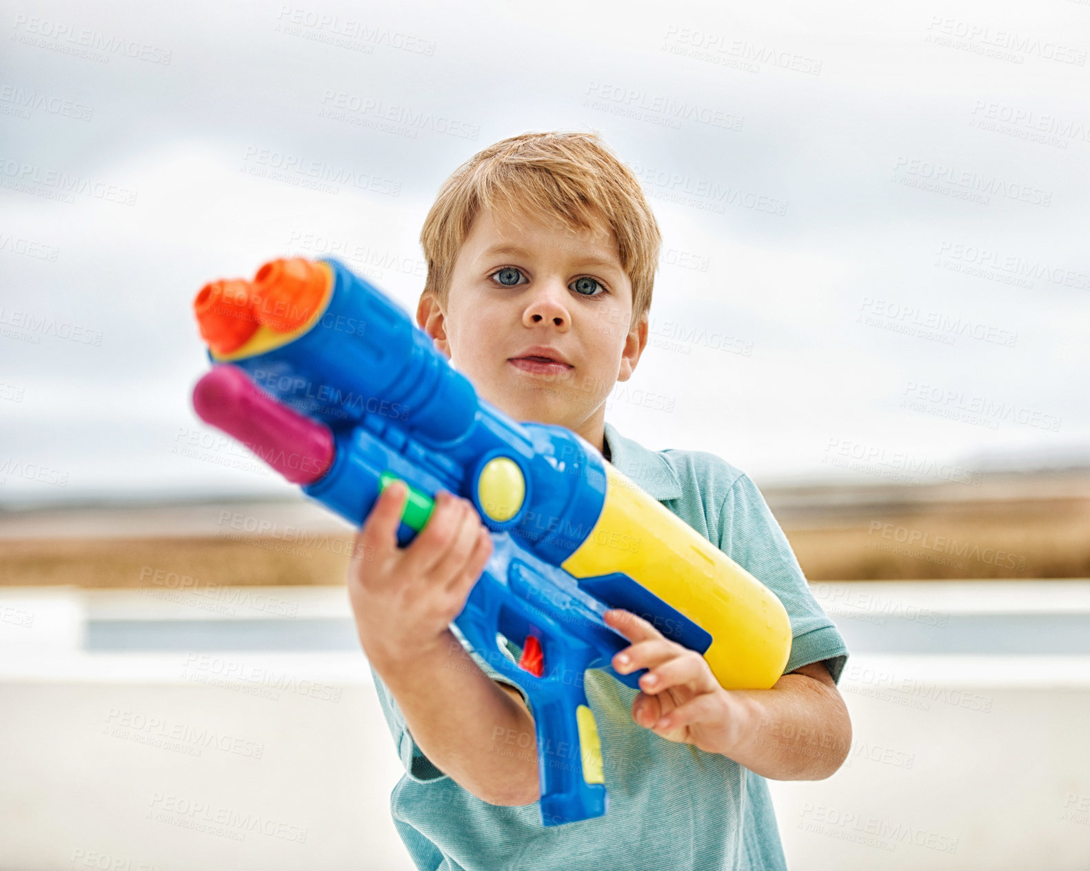 Buy stock photo Portrait of a cute young boy holding a water gun outside