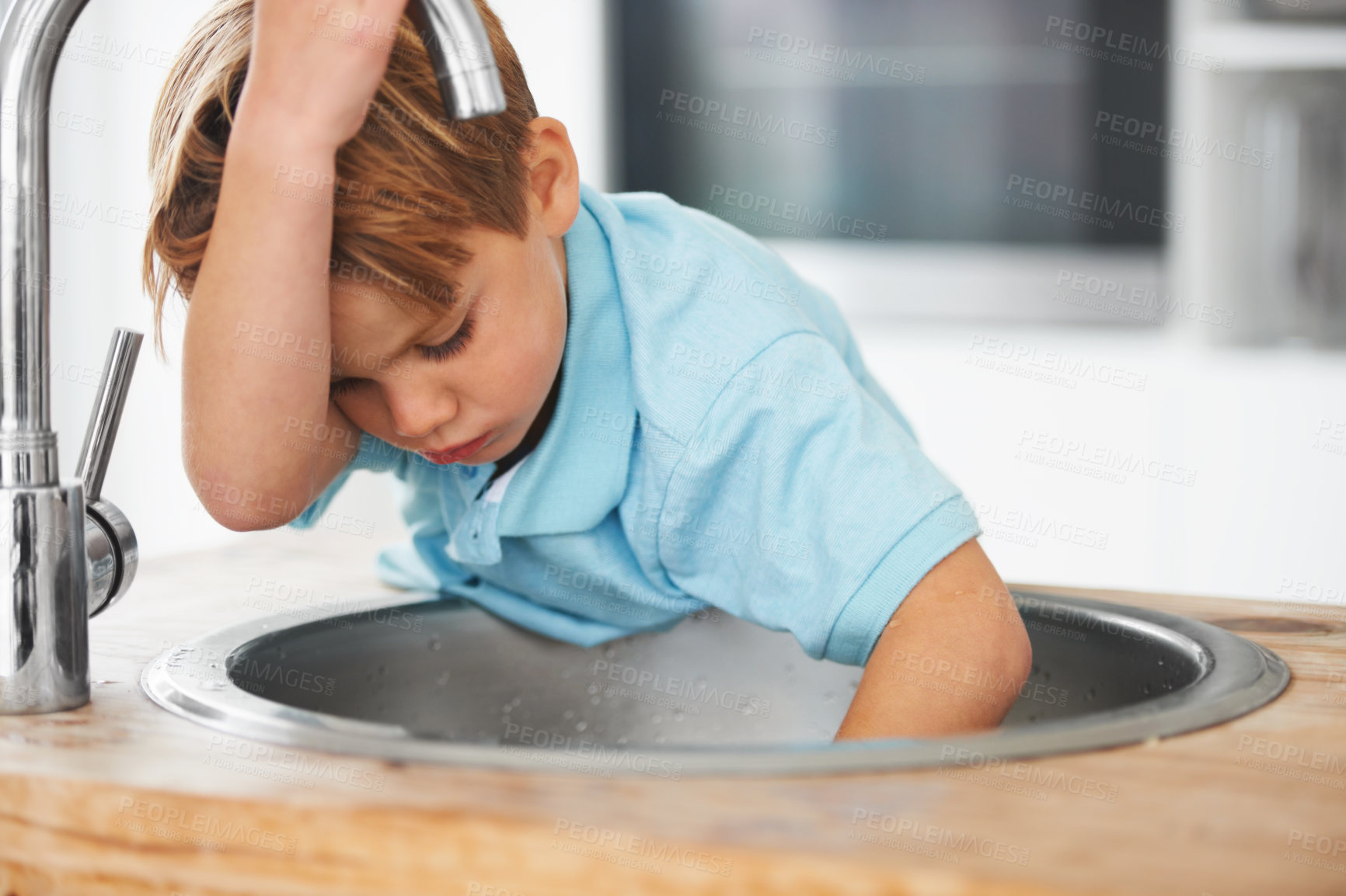 Buy stock photo Children, fantasy and a boy in the kitchen sink, playing a game in his home as a plumber character. Kids, basin and counter with a young male child in a modern apartment for imaginary plumbing