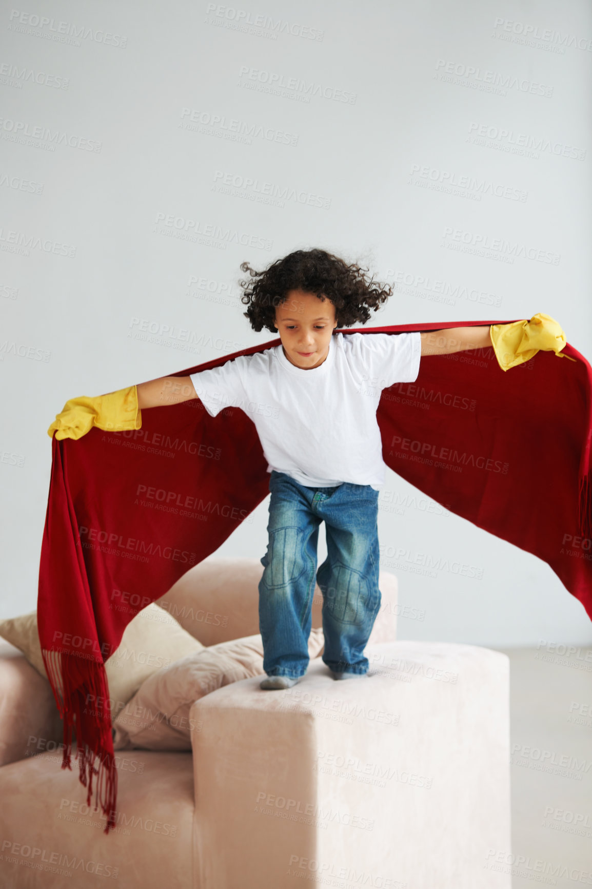 Buy stock photo A cute young boy pretend to fly his lounge sofa holding a blanket like a superhero's cape