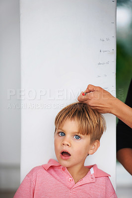 Buy stock photo Portrait of a shocked young boy having his height measured by his mother on the kitchen wall