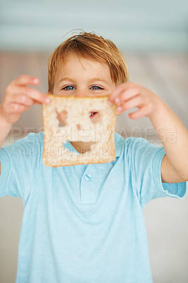 Buy stock photo Shot of a little boy holding up a slice of bread with a cut out smiley face