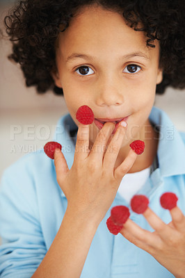 Buy stock photo Cute, portrait and boy child with raspberries at home with a health, wellness or diet snack. Smile, nutrition and young kid from Mexico eating healthy berry fruit on his fingers for a treat at home.