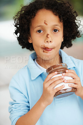 Buy stock photo Cute, portrait and child with chocolate spread at a home with delicious, sweet snack or treat. Smile, happy and face of young boy kid from Mexico eating nutella jar licking lips at modern house.