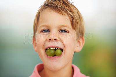 Buy stock photo Shot of a boy stuffing two grapes in his mouth