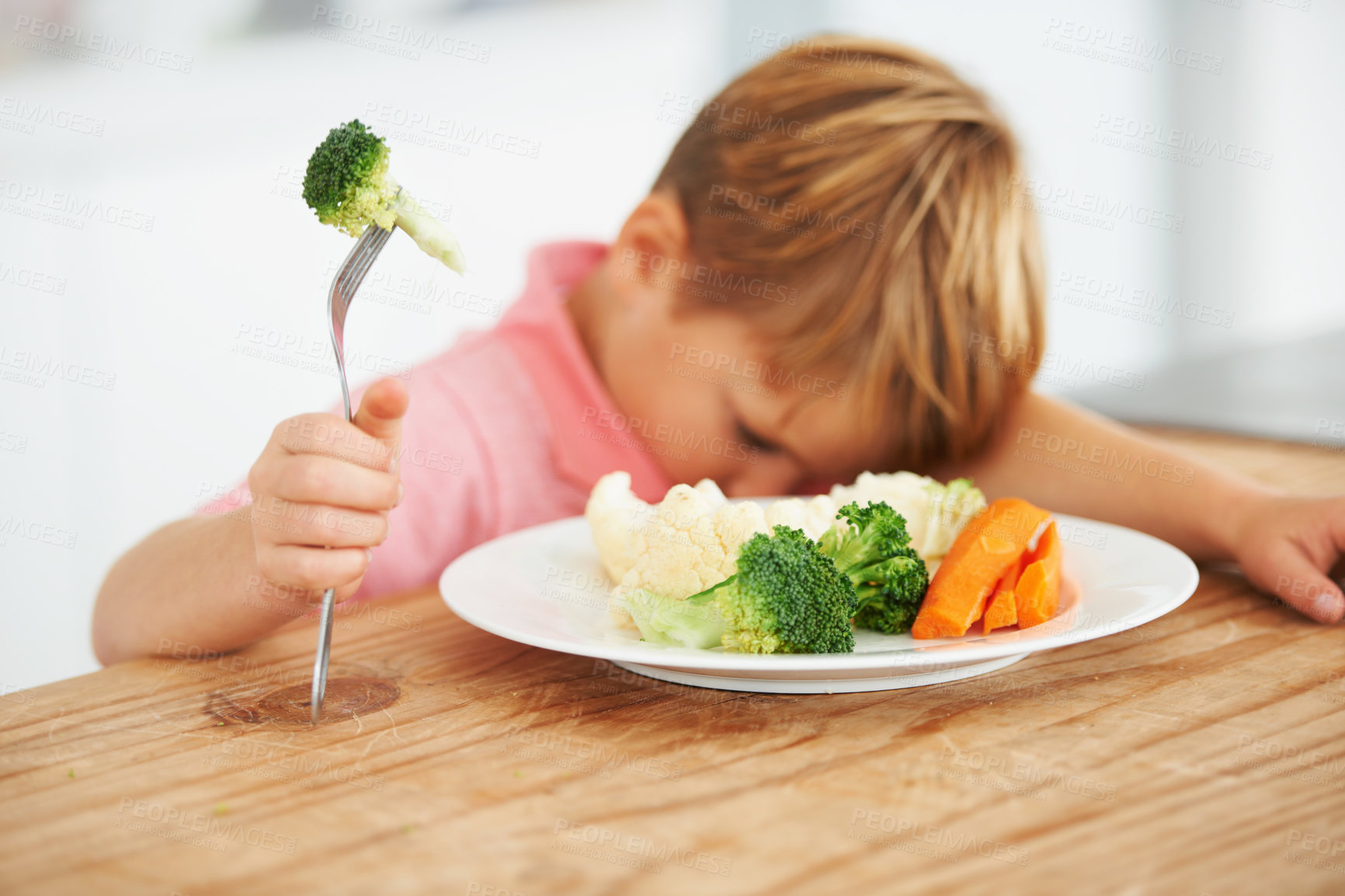 Buy stock photo A little boy very unhappy with having to eat vegetables