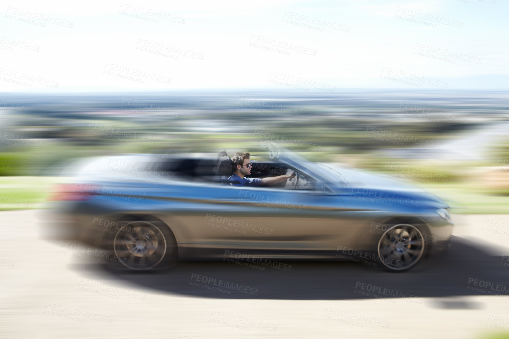 Buy stock photo A young man speeding on the open road in his silver convertable