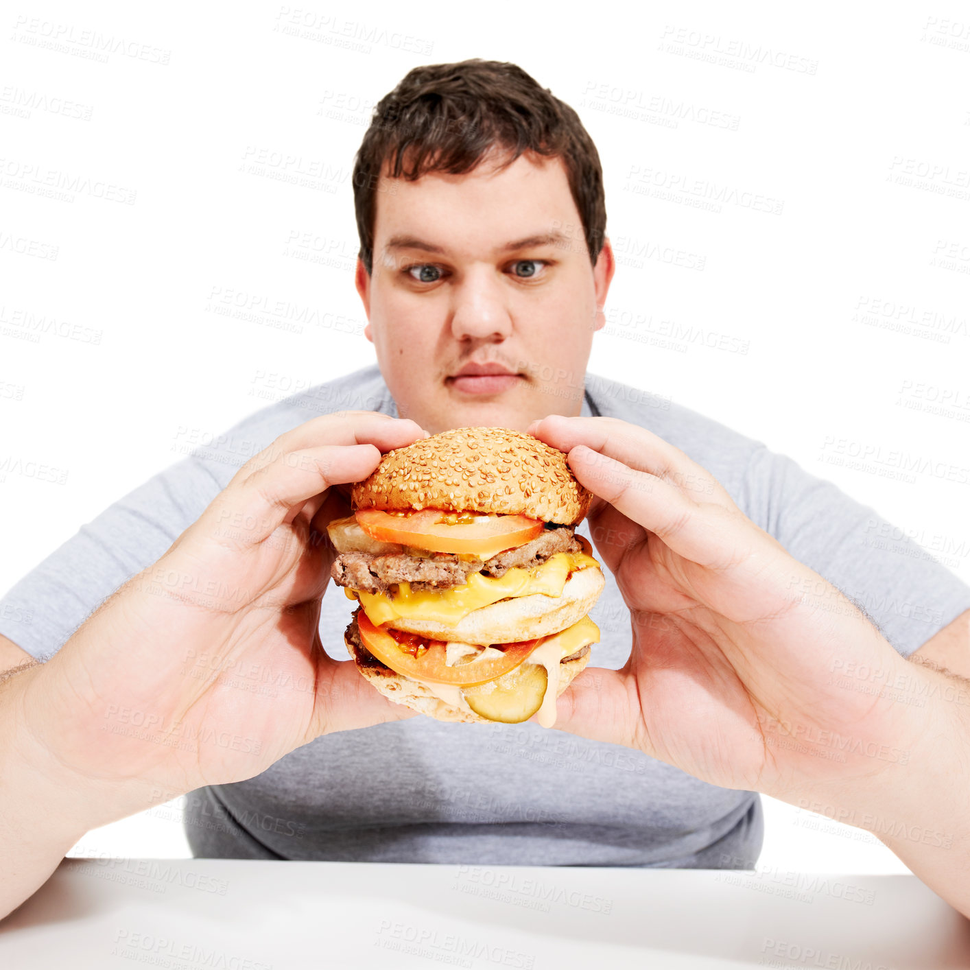 Buy stock photo Plus sized, eating and man holding burger, unhealthy diet and isolated hungry person and white background. Junk food, weight loss and healthcare problem, male with bad food addiction in studio.