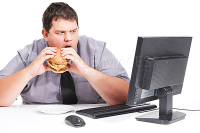 Buy stock photo A young man eating his lunch at his desk at work while staring with mouth agape at his monitor - unhealthy eating habits
