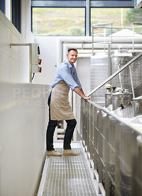 Buy stock photo Industry, confidence and portrait of a wine maker standing by stainless steel machines in factory. Proud, smile and full length of a male winery employee doing alcohol production in cellar warehouse.