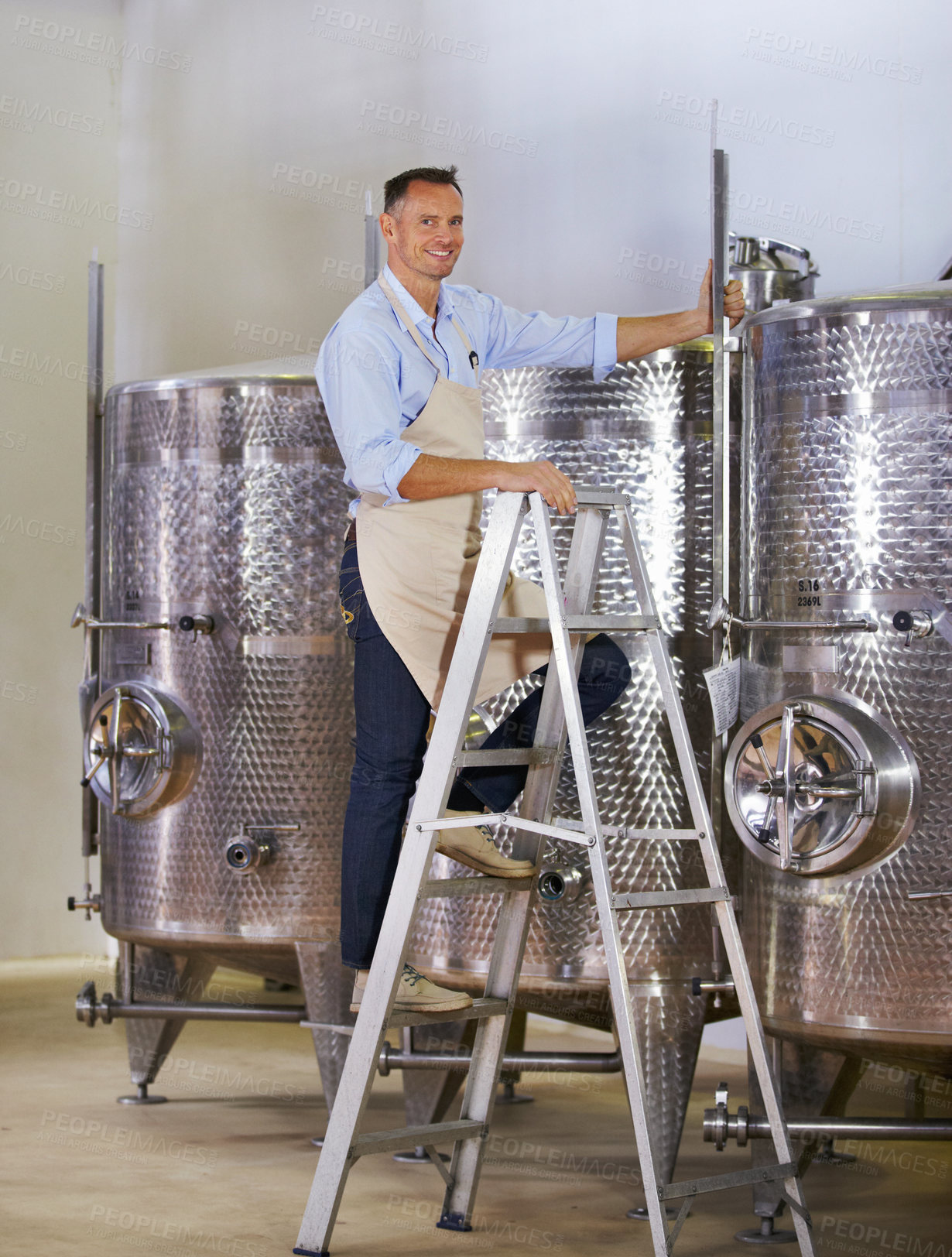 Buy stock photo Portrait of a mature wine maker standing next to his steel vats in his cellar