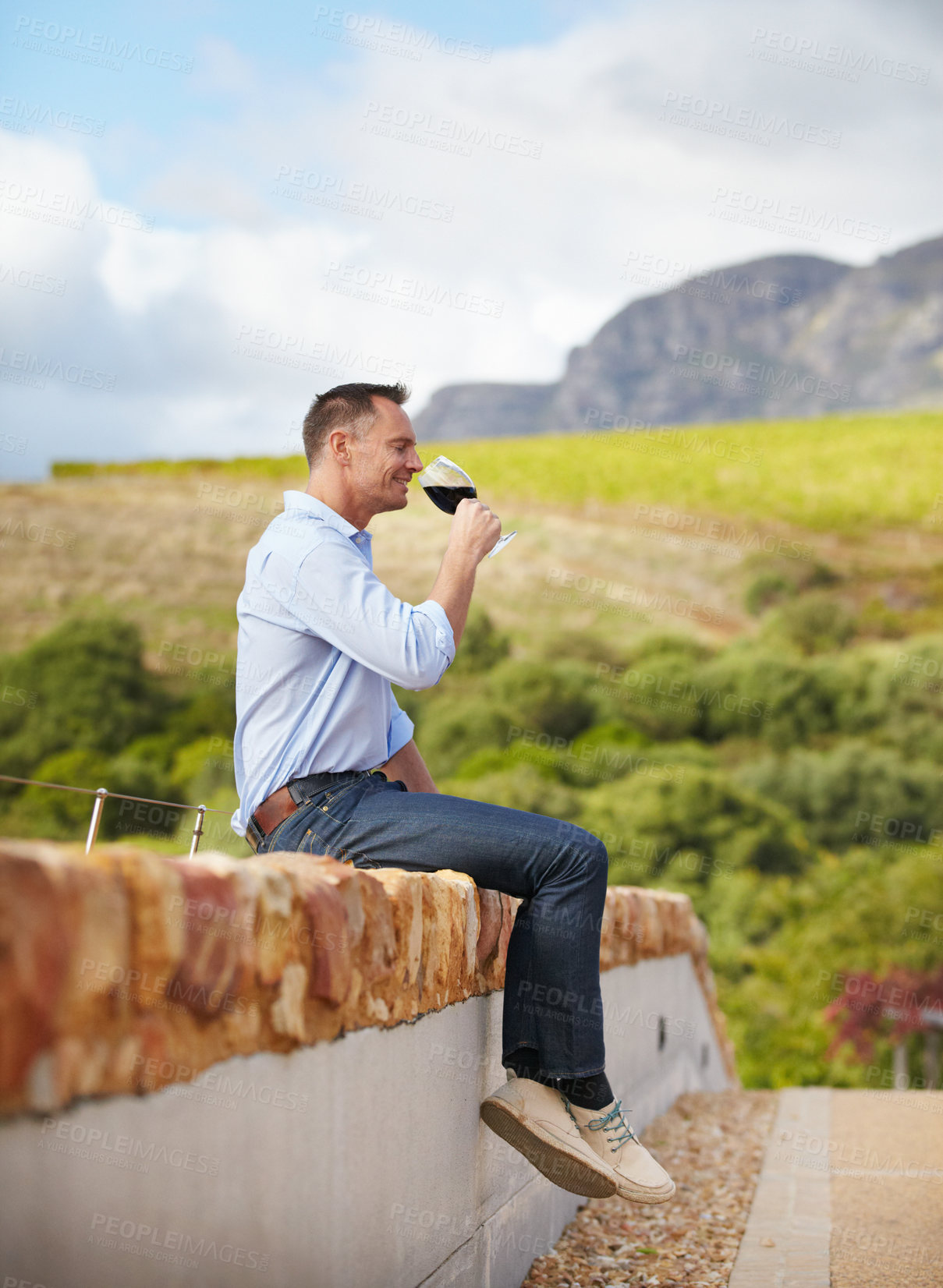 Buy stock photo A mature man sitting on wall and enjoying a glass of red wine