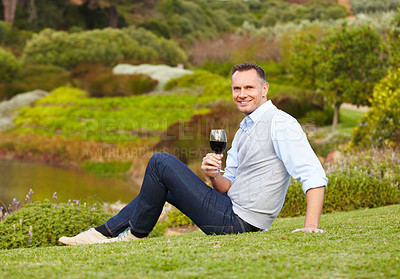 Buy stock photo Mature man with red wine outdoor, relax with smile in nature with alcohol drink, leisure and travel to countryside. Happy male person with alcoholic beverage in glass, satisfied and relaxing in park