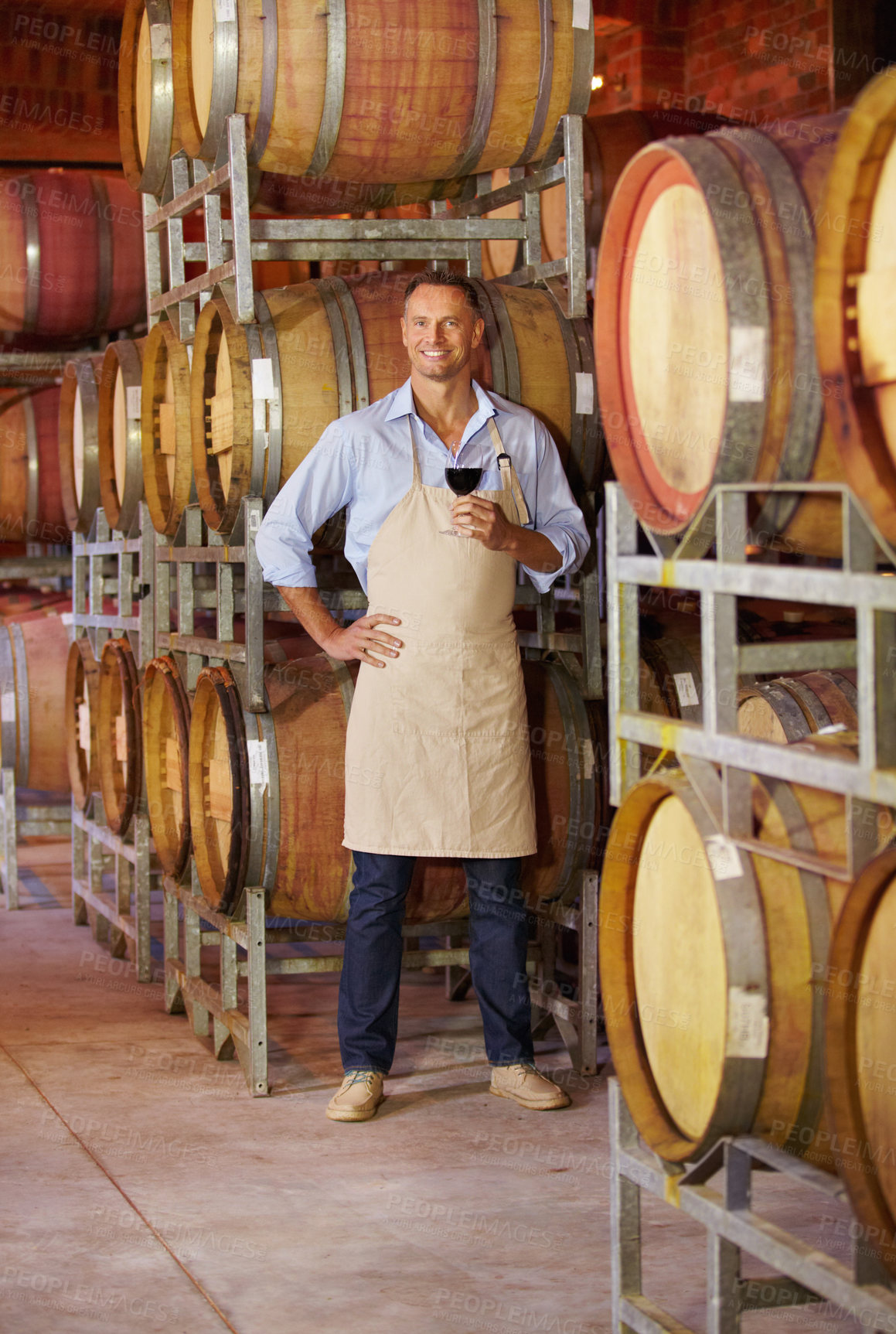 Buy stock photo Portrait of a mature wine maker tasting a glass of red wine while in his cellar